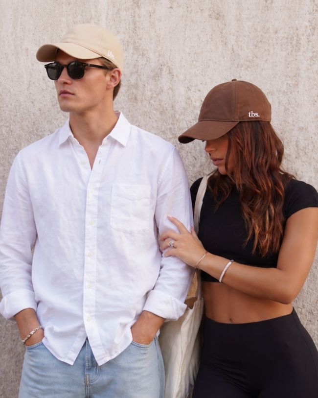 Couple posing in front of a wall with silk-lined caps.