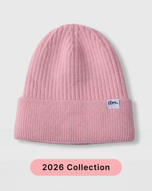 A light pink ribbed knit beanie hat with a folded cuff and a small white 'dbs.' label on the side, shown on a light gray background with a pink '2026 Collection' banner at the bottom. silk lined